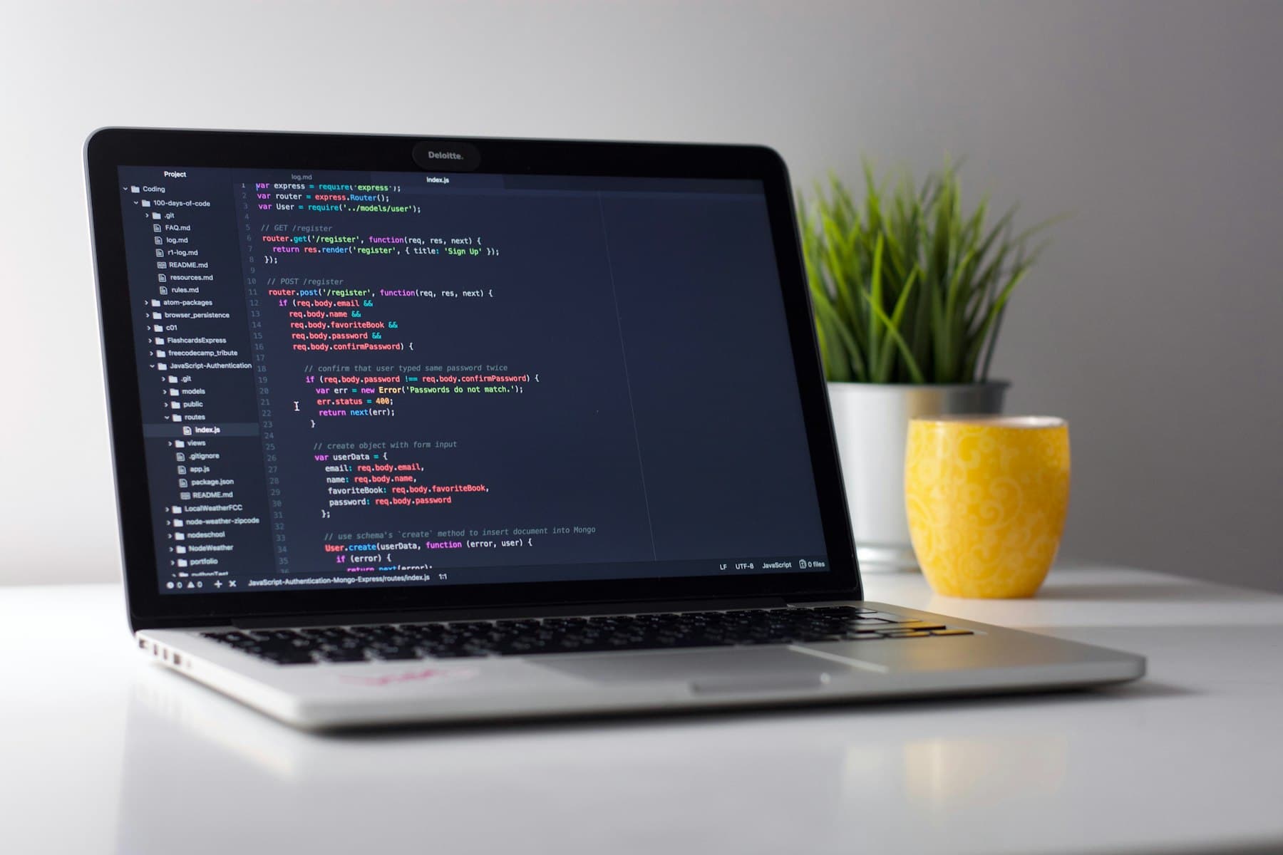 Aufgeklappter Laptop mit Code-Editor auf einem hellen Schreibtisch