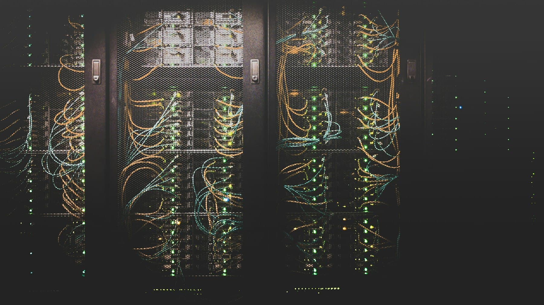 Serverschränke mit Netzwerkverkabelung und Status-LEDs in einem dunklen Serverraum